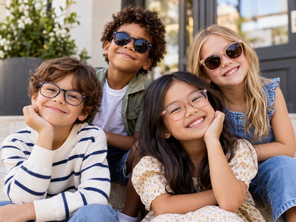 Quattro bambini sorridenti con occhiali da vista e da sole